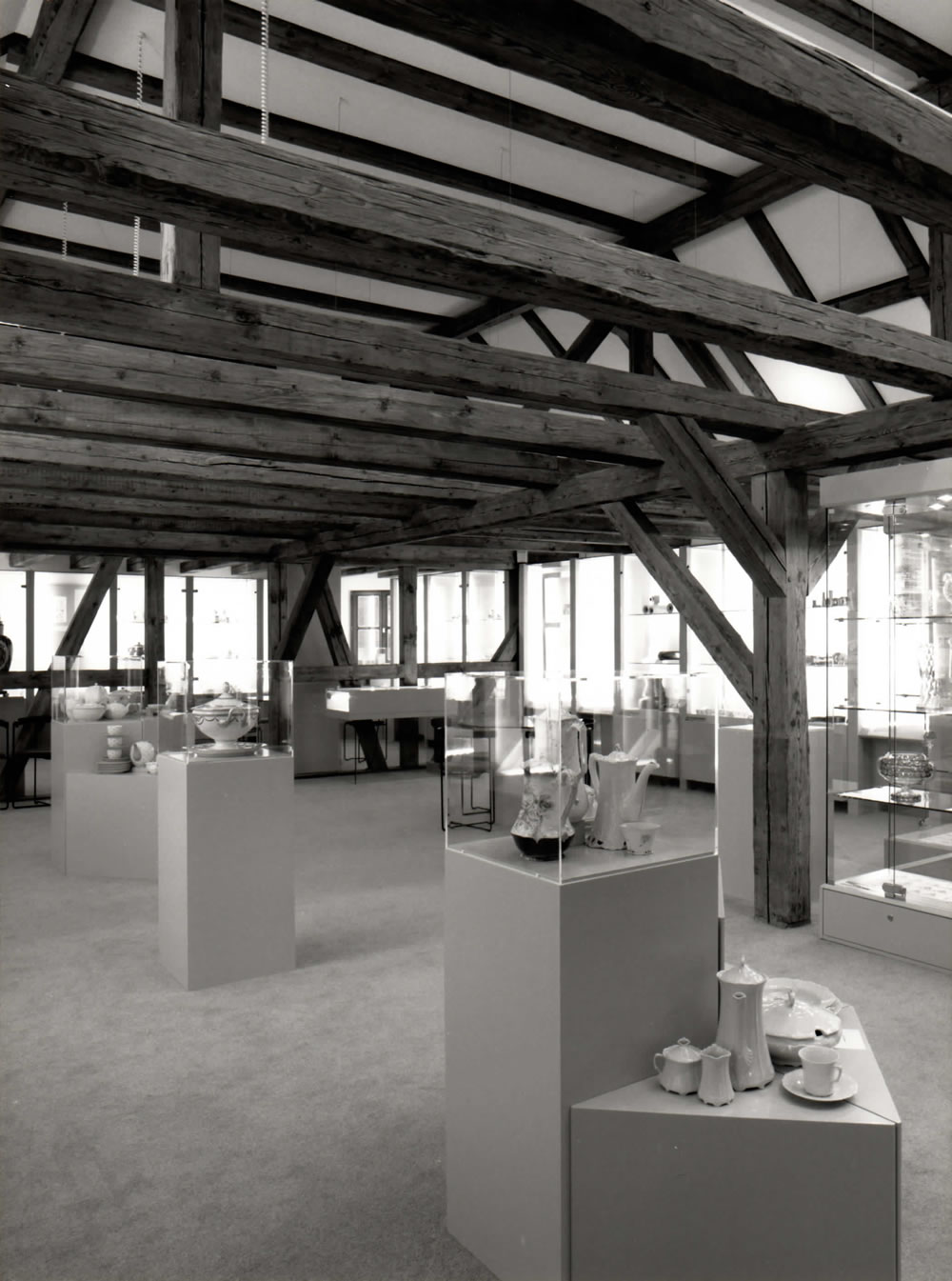 Ausstellungsraum mit Glasvitrinen und sichtbaren Holzbalken.